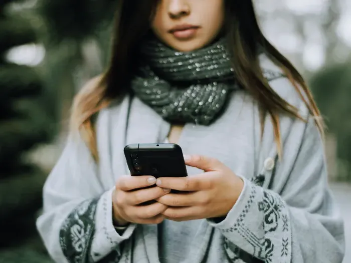 Young woman outdoors using a smartphone to find nearby services and reviews with the Local Biz World directory